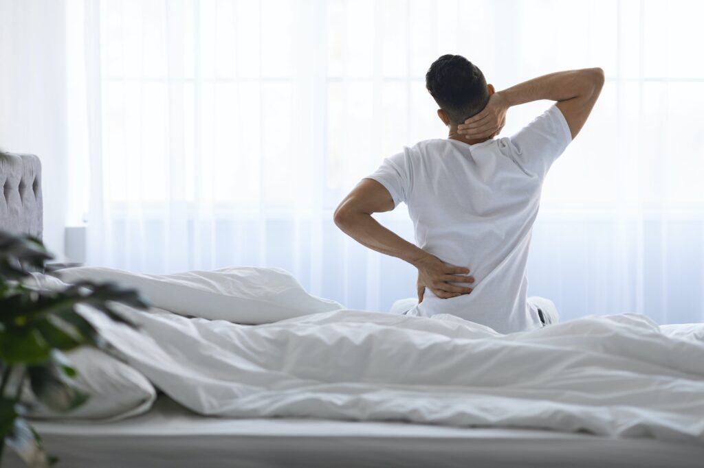 Unrecognizable Young Man Waking Up In Morning With Neck And Back Pain